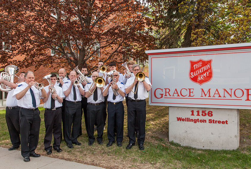 Members of the band pose with their instruments next to the Grace Manor sign.